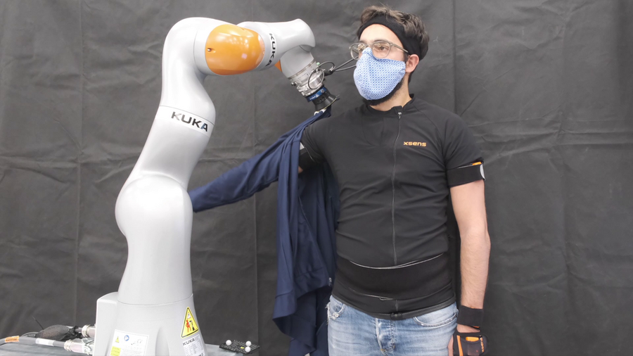 Photo of a robotic arm pulling a sleeve onto a human’s arm