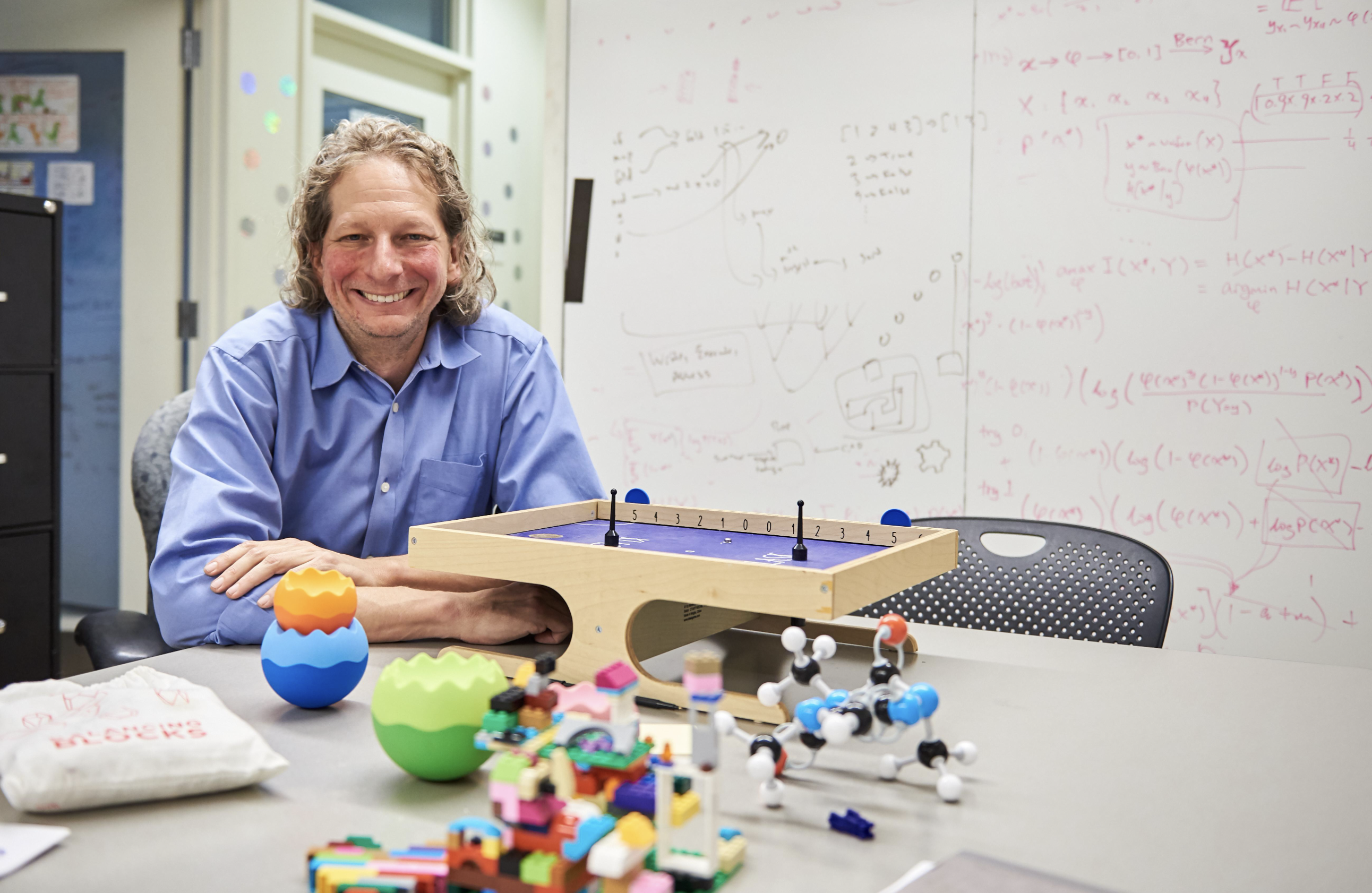 Tenenbaum sits at a desk covered in legos and colorful modular toys